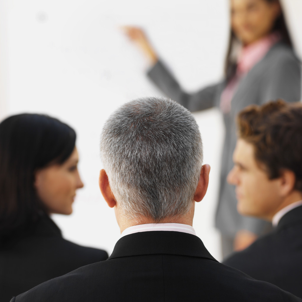 Businesswoman giving presentation to three business executives --- Image by © Royalty-Free/Corbis